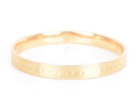 A 1920s 15ct gold bangle, having engine turned decoration with bands of geometric designs, hallmarked London 1923, 77.3mm dia