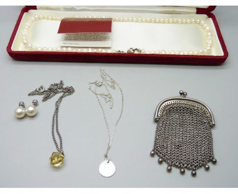 A metal chainmail purse, a silver necklace, a pair of faux pearl earrings, a string of pearls and a necklace with a faceted y