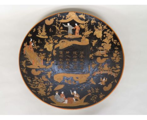 A modern Chinese black ground ceramic charger, all over painted with figures in fragments of landscapes around a central scro