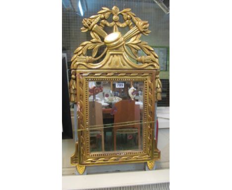 A gilt wood framed mirror with tassel decoration and torch and drum cresting
