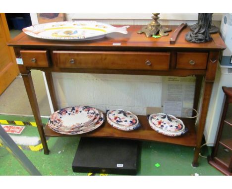 A walnut side table with three drawers and lower shelf