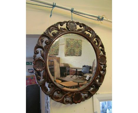 A circular mirror in carved oak shell frame