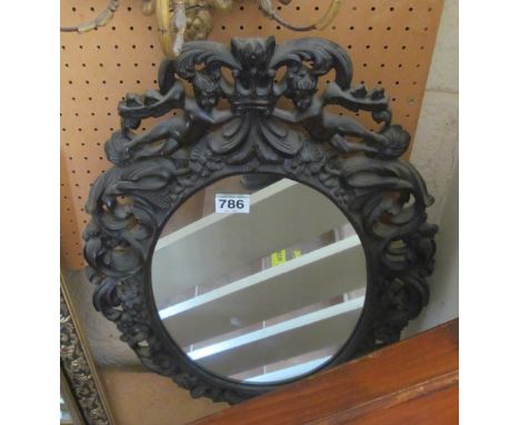 A carved pieced frame oval mirror with cherubs holding a crown to top