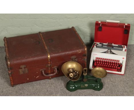 A wooden bound travel trunk along with a cased Olympia Monica typewriter and set of vintage weighing scale.  