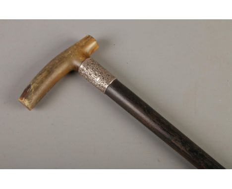 A silver collared ebonised walking stick, with horn handle. Collar assayed for London, 1910 by J Howell &amp; Co Ltd.  