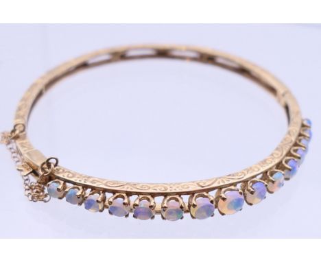 A 9 ct gold opal bangle bracelet.  6 cm diameter. 10.9 grammes total weight. 