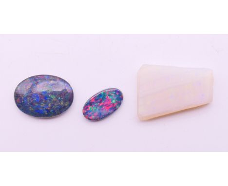 Two loose black opals and a white opal.  Black opals 2 cm high and 1.5 cm high, white opal 2 cm x 1.7 cm at widest part.