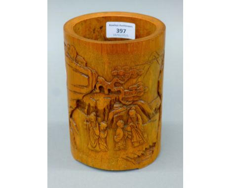 A bamboo brush pot with scene carved in relief and calligraphy inscription to reverse. 17.5 cm high.