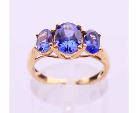 An 18 K gold three-stone tanzanite ring. Ring size M.