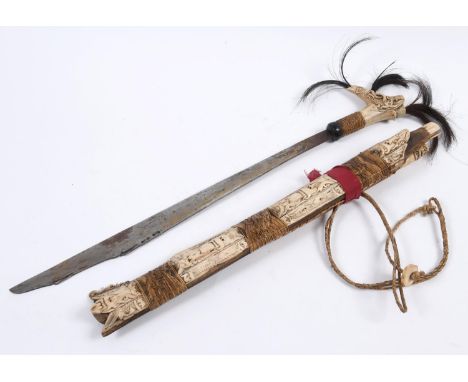 A BORNEO HEAD HUNTERS SWORD. A highly decorative head hunters sword, the grip with three plumes of dark hair on a carved bone