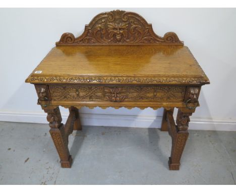 A Green Man carved oak hall/side table with a drawer - with good light colour and polished finish - Height 98cm x 89cm x 43cm