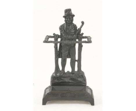 An iron 'Ireland' stick stand,late 19th/early 20th century, the backplate cast as a man holding a club, the support rail cast