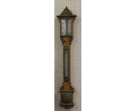 A Victorian carved pollard oak stick barometer with opaque glass scales and adjuster.