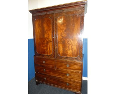 A Victorian figured mahogany linen press with two short and two long drawers below hanging compartment (minus trays), surmoun