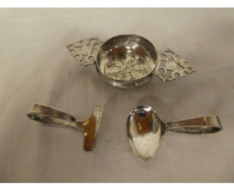 A silver circular tea strainer with pierced handles, Sheffield marks and a silver child's spoon and pusher (3)