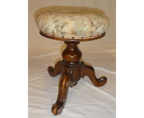 A Victorian walnut revolving piano stool with floral upholstered circular top on tripod base