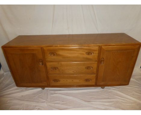 A 1960's Ercol light elm rectangular sideboard with three central drawers and cupboards enclosed by two panelled doors