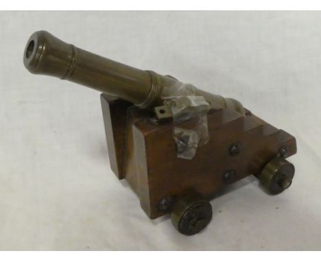 An old bronze model canon with 7" barrel on polished wood stepped base with brass mounted wheels