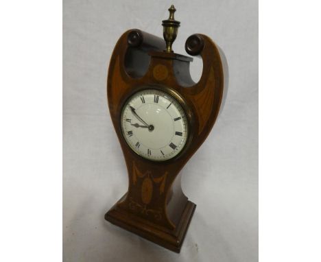 An Edwardian Art Nouveau style mantel clock with enamelled circular dial in inlaid mahogany scroll arched case surmounted by 