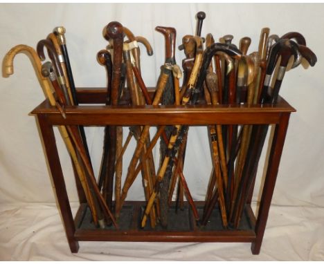 A mahogany three-section stick stand containing a collection of over 40 various walking sticks and canes including silver mou