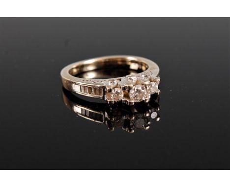 A 14k diamond ring, the central graduated three round brilliant cut diamonds, claw mounted with quarter set with baguette cut