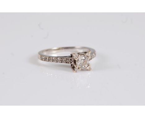 A diamond ring, the central round brilliant cut diamond set with an additional small round diamond to each claw, with half se