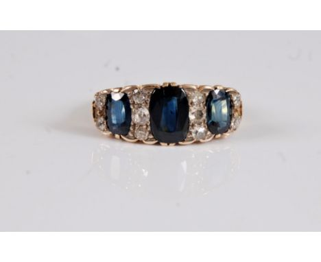 An 18ct sapphire and diamond ring, the central sapphire approx. 9.2mm long, set to either side with three small old cut diamo