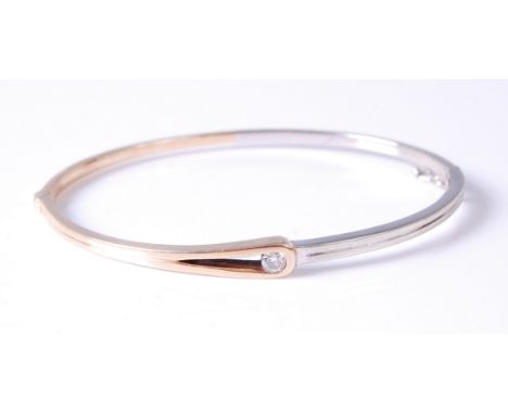 A contemporary 9ct yellow and white gold hinge bangle, set with a single brilliant cut diamond weighing approx 0.12ct, 10g, 6