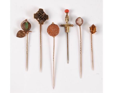 Six various stick pins: to include a Celtic cross stick pin; a stick pin set with a round seed; an oval citrine stick pin; a 