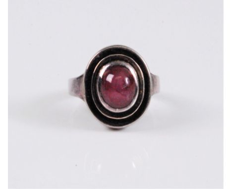 A star ruby ring, the oval star ruby cabochon, approx. 8.8mm long, collet mounted in a tow tier stepped surround, approx. 17.