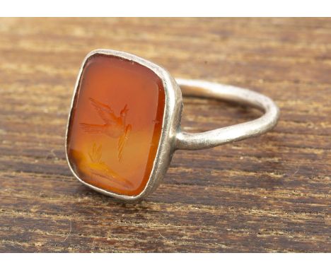A 19th Century carnelian silver set signet ring, with intaglio carving depicting a songbird, ring size J, together with an ov