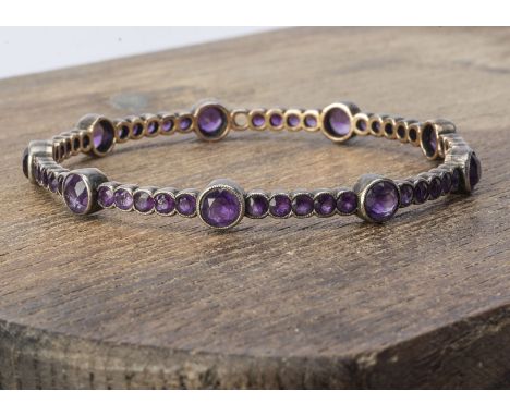 An amethyst yellow and white metal circular bangle, the round cuts in collet settings, 6.6cm interior diameter, yellow metal 