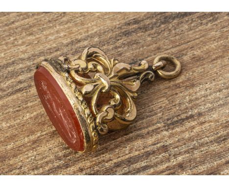 A 19th Century pinchbeck and carnelian fob, with stylised fleur de lys pierced mount with an oval carved intaglio of classica