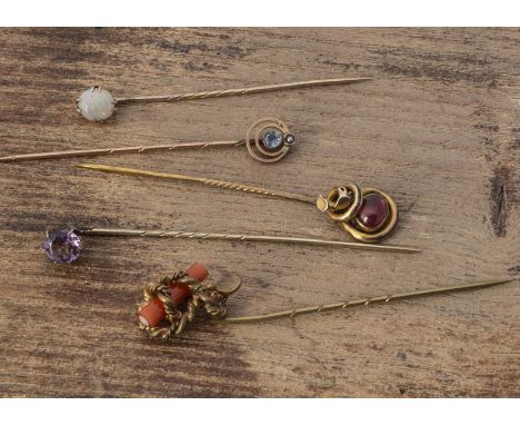 A 19th Century garnet cabochon knot stick pin, on a base metal pin together with another with simulated seaside stick of rock