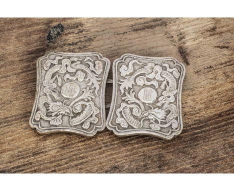 An early 20th century Chinese white metal chassed belt buckle, with dragon and pearl with Chinese characters, marked to rever