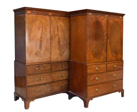 Near pair of Georgian mahogany linen presses, each having two oval cross banded panel doors, beneath fluted and inlaid patera