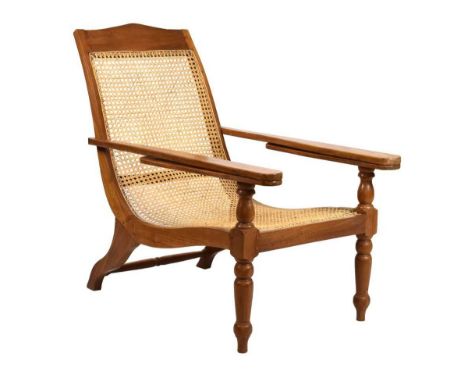 Teak plantation style chair, with downswept rattan back and seat with hinged arms, raised on baluster fore legs, 64cm wide x 