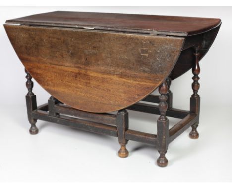 An 18th Century English oak gate-leg Table, the demi-lune flaps supported by a gate leg with turned pillars and similar centr