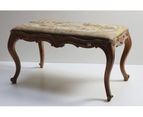 A Victorian walnut Window Stool, the drop in seat with floral tapestry decoration, with shaped frieze on cabriole legs. (1)