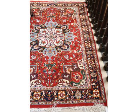 An attractive Turkish red ground Carpet, with rosette centre and floral corners, slim blue ground similarly decorated border,