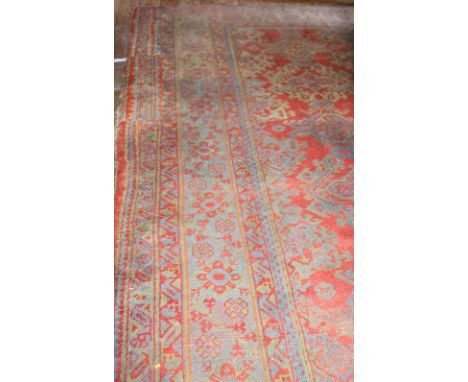 A large Feraghan Wool Carpet, semi-antique, the rich red ground decorated with all-over foliate motifs in blue and off-white 