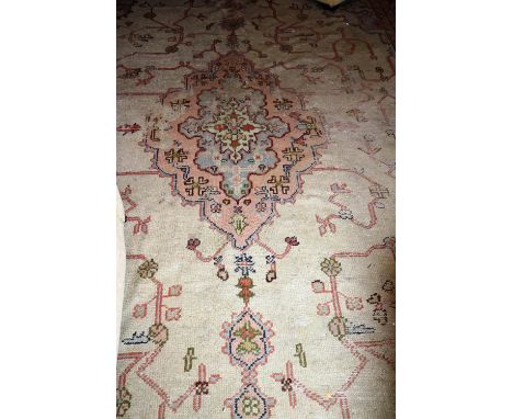 An old Oriental Indian Carpet, fawn ground, pink border, approx. 16' x 12'. (1)