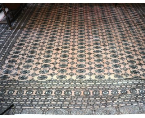 A large and attractive pink ground woolen Carpet, the central panel with circular motifs surrounded by multiple borders, appr