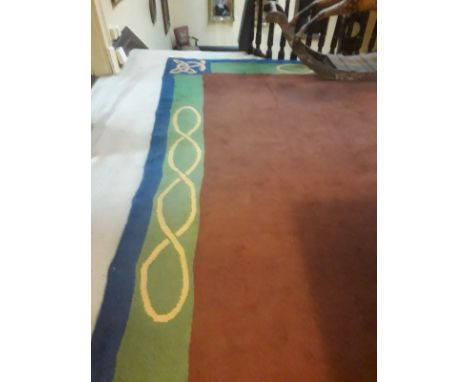 A large Irish Donegal Carpet, the large plain brown central panel with a slim green and blue border with Celtic design, appro