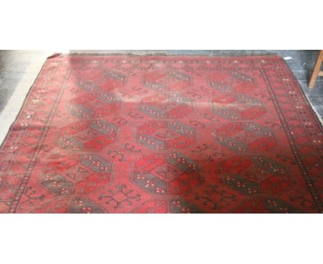 A red ground woolen Carpet, with multiple lozenge central design and slim border, approx. 305cms x 206cms (10' x 7'7"). (1)