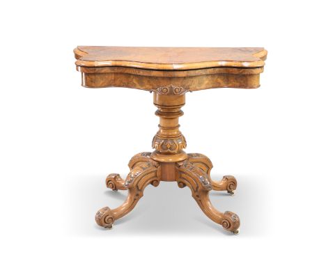 A VICTORIAN BURR WALNUT FOLDOVER CARD TABLE, of serpentine outline, raised on a turned and carved stem continuing to four lea