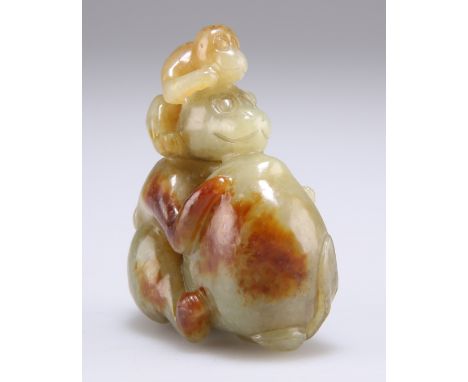 A CHINESE JADE CARVING, of a juvenile monkey, sitting on the shoulders of an adult monkey clasping a large fruit, the stone o
