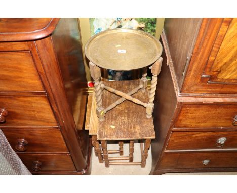 An Eastern engraved brass tray on folding stand; a nest of oak coffee tables; a coloured print and a still life print