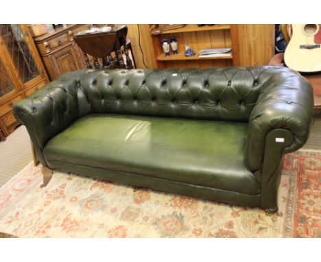 A green leather effect upholstered button back, drop arm three-person Chesterfield design settee 