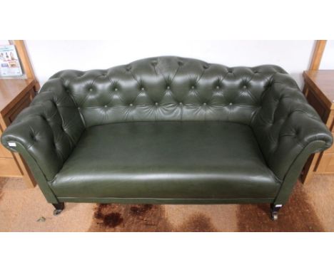 A modern green leatherette upholstered humped back button Chesterfield style settee on short tapering legs with brass castors